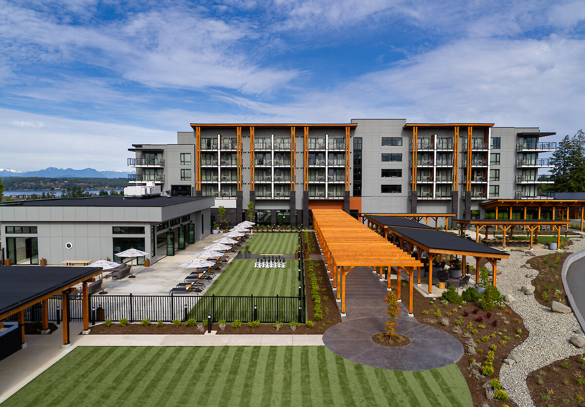 An exterior view of Naturally Pacific Resort, looking at it from the road, through bushes and past the parking lot.