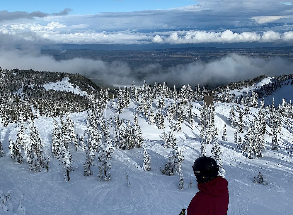 A skiier goes down a ski-hill at Mount Washington. Low clouds show the distant mountain in the background