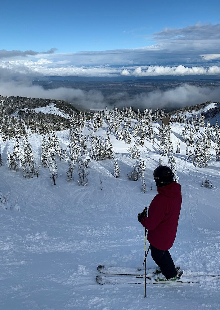 A skiier goes down a ski-hill at Mount Washington. Low clouds show the distant mountain in the background