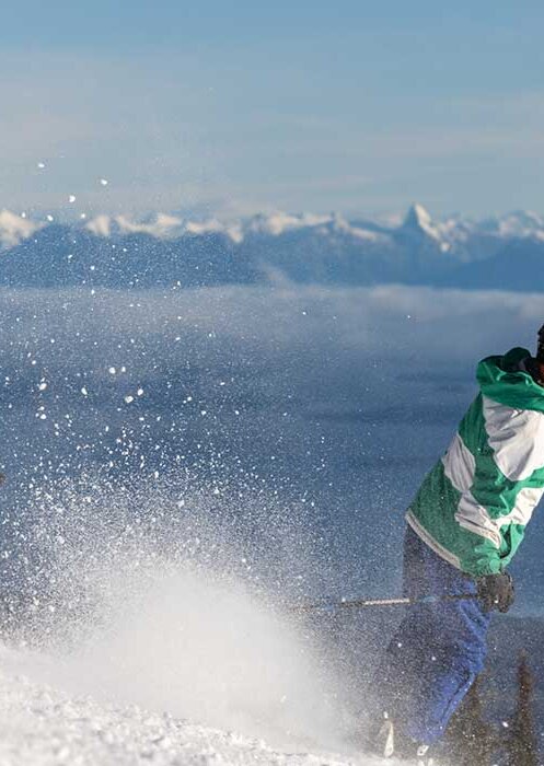 A skiier goes down a ski-hill at Mount Washington. Low clouds show the distant mountain in the background