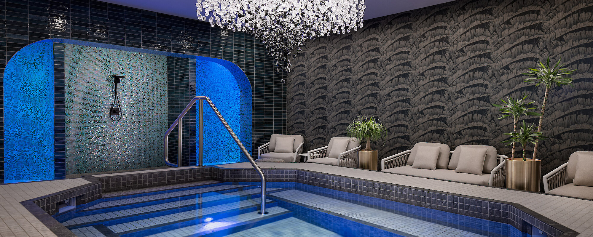 mineral pool and experience showers with a beautiful chandelier over the pool and loungers to the side
