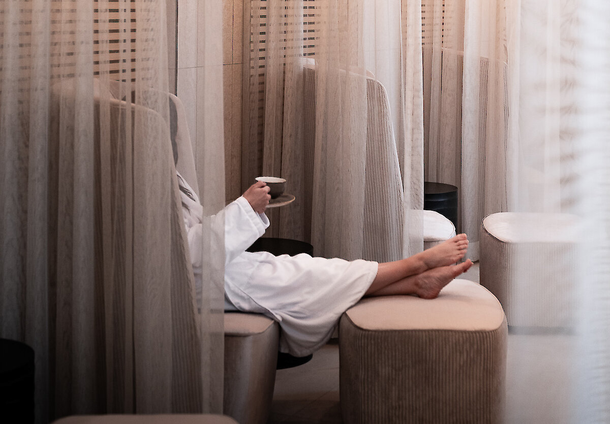 luxurious entrance of immersion spa and wellness looking at the tiled front desk with the logo on the wall and a receptionist at the desk sitting at her computer